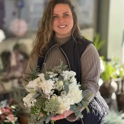 Une fleuriste de L’AGAVE présente un bouquet de mariée blanc et vert dans la boutique